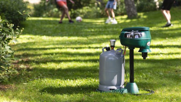 Mosquito Magnet etualalla ja taustalla nuoria pallopelien parissa.